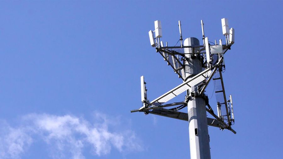 Cell tower sitting against a blue sky with a cloud