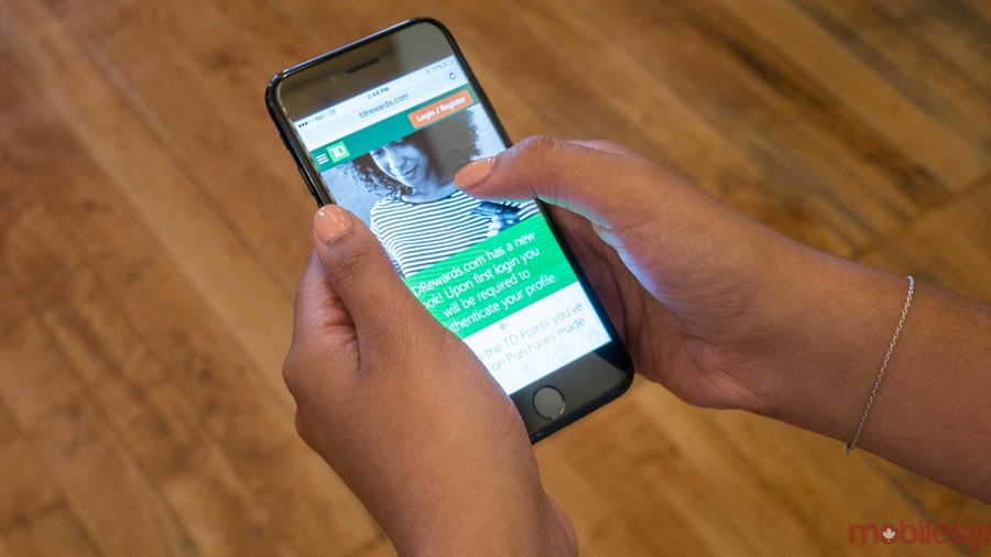 An image showing a hand holding an iPhone 7 with the TD Rewards website on-screen