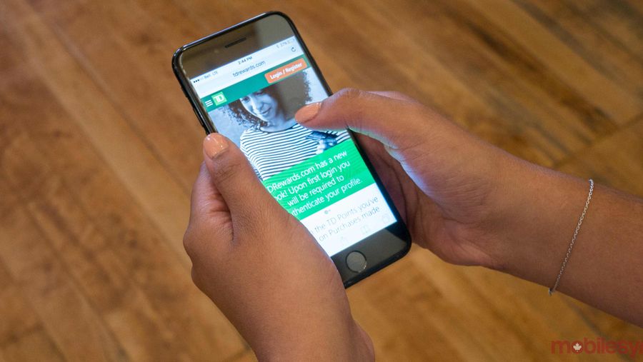 An image showing a hand holding an iPhone 7 with the TD Rewards website on-screen