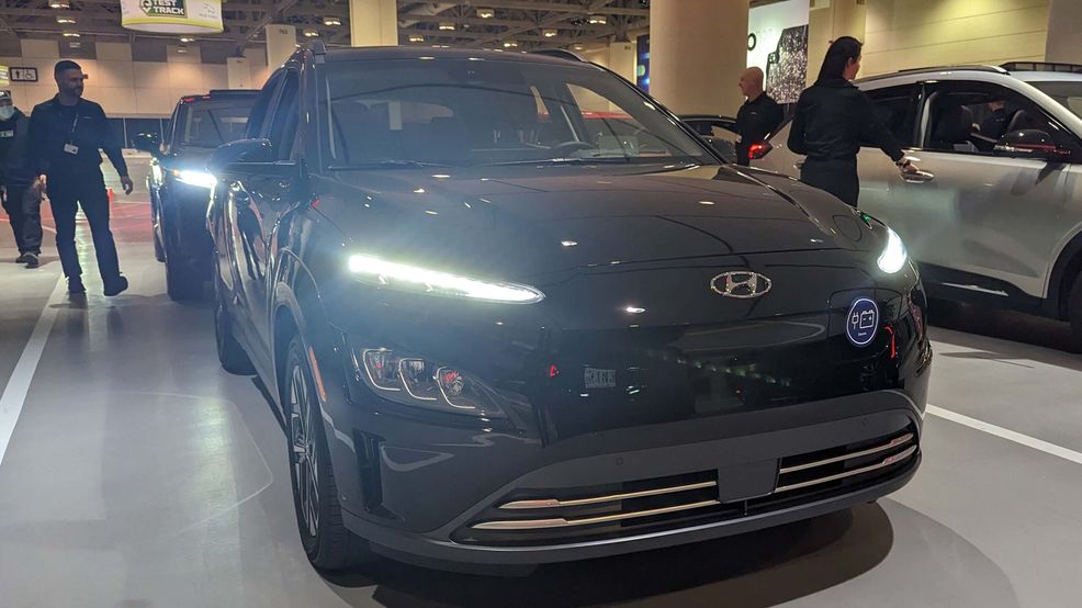 Hyundai Kona EV with bright headlights.
